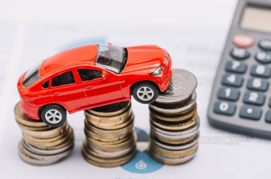 Red toy car on coin stacks with calculator, symbolizing car financing in 2025.
