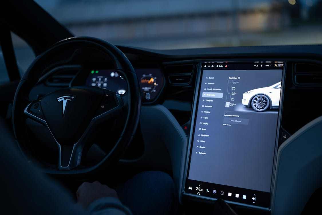 Tesla interior showcasing autonomous driving systems with digital touchscreen controls and Autopilot features on display.