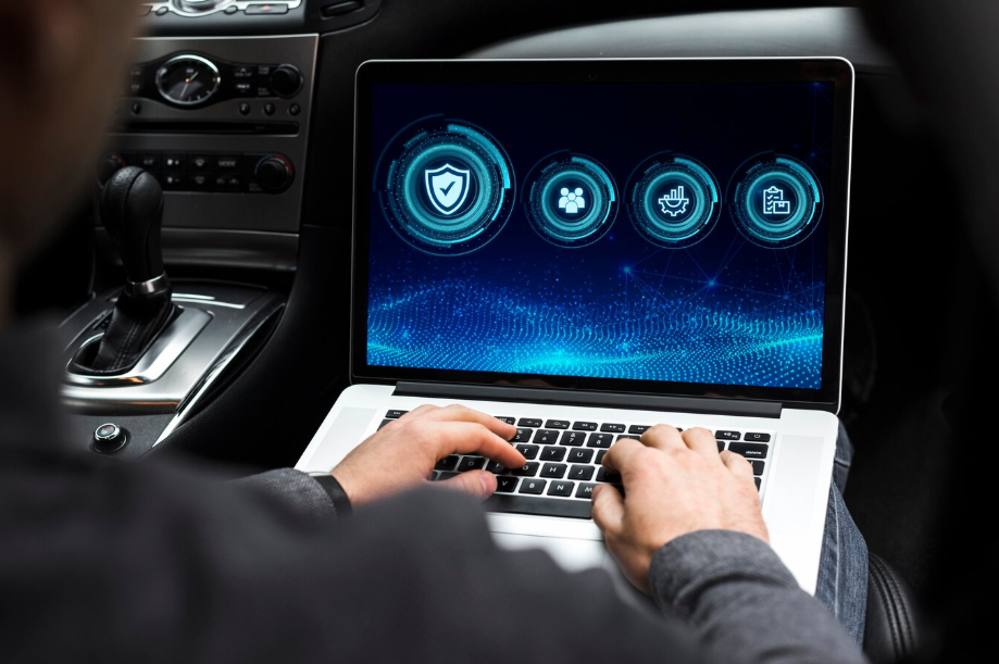 Person using a laptop to test cybersecurity for connected cars inside a vehicle cockpit.