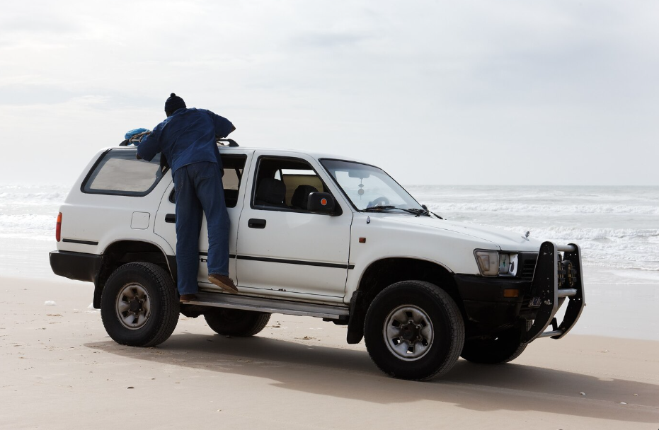 Man loading gear on a white SUV, showcasing large vehicle size and outdoor use