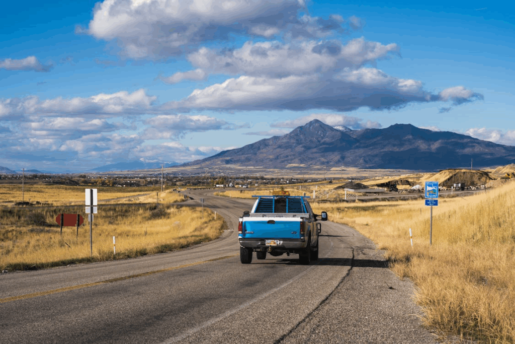 Pickup truck driving along a scenic rural highway with mountain views