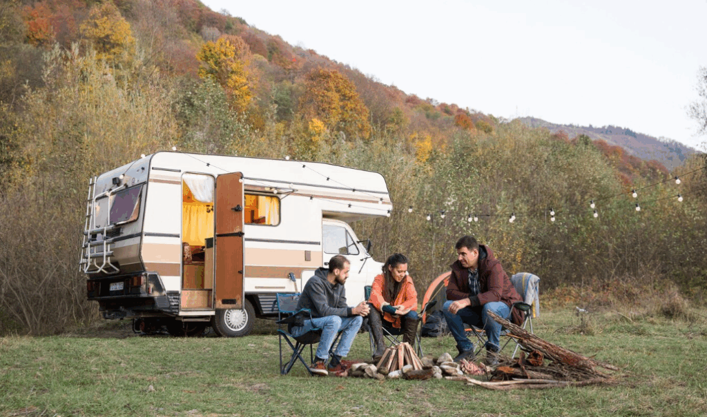 Campers with a vintage RV in a scenic fall forest, showcasing a cozy off-grid camping setup.