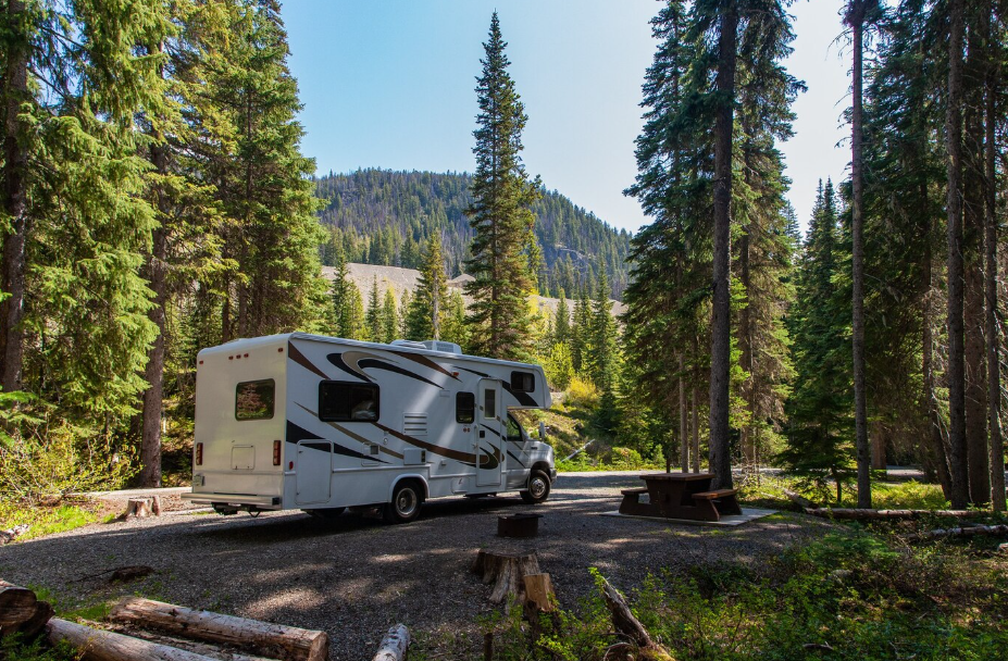 Truck-friendly destination near Atlanta with RV parked in forest campground surrounded by pine trees and mountains in the background.