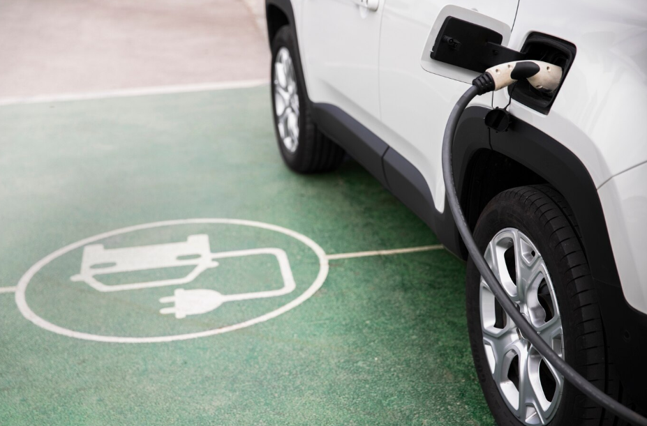Electric vehicle charging at designated EV parking spot with plug-in cable connected to white SUV