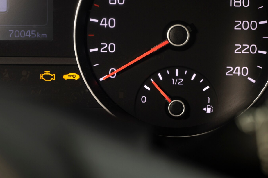 Car dashboard showing check engine light and fuel gauge near empty